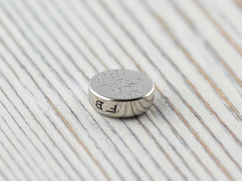 Pu&ograve; includere: Una batteria per orologio argentata con il testo "392/1.5V  Made in Japan  LR44  AG13  GP" stampato sulla parte superiore.