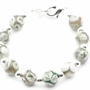 Op de afbeelding: Een zilveren armband met groene en witte agaat kralen.