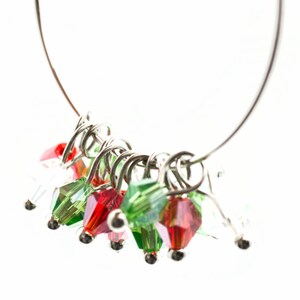 May include: A silver ring with a series of red and green crystal beads attached to it. The beads are arranged in a cluster and hang from the ring.