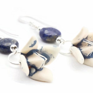 May include: A pair of silver earrings with blue and white ceramic flower charms and blue lapis lazuli beads.