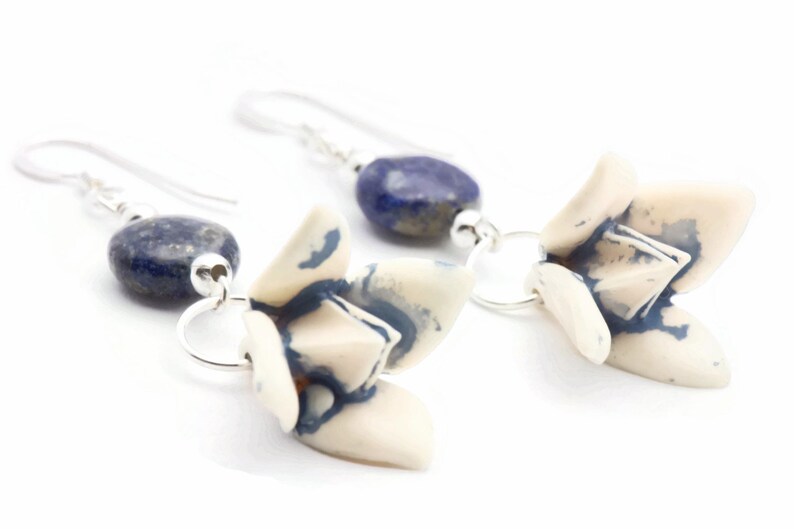 May include: A pair of silver earrings with blue and white ceramic flower charms and blue lapis lazuli beads.
