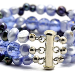 May include: A multi-strand bracelet with a silver clasp. The bracelet is made of blue and purple glass beads and pearls.