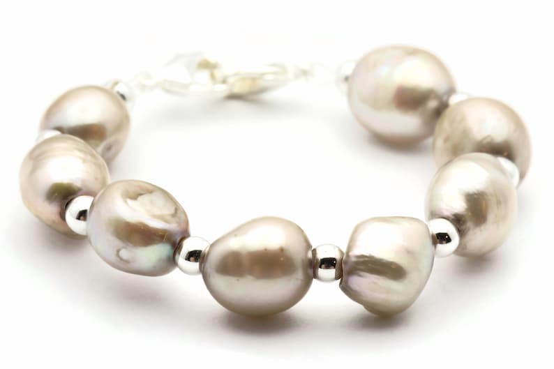 Peut inclure: Un bracelet en perles avec des accents argent&eacute;s. Le bracelet pr&eacute;sente une s&eacute;rie de grosses perles de forme irr&eacute;guli&egrave;re de couleur gris clair.