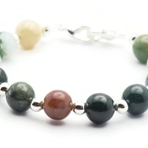 Pode incluir: Um bracelete feito de contas de &aacute;gata verde, marrom e creme com espa&ccedil;adores prateados e um fecho prateado.