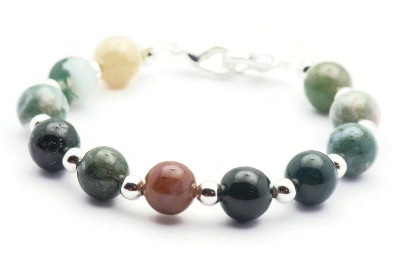 Pode incluir: Um bracelete feito de contas de &aacute;gata verde, marrom e creme com espa&ccedil;adores prateados e um fecho prateado.