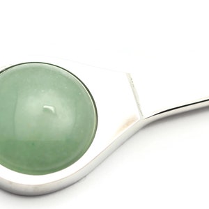 Puede incluir: Un llavero de plata con una piedra de jade redonda verde.