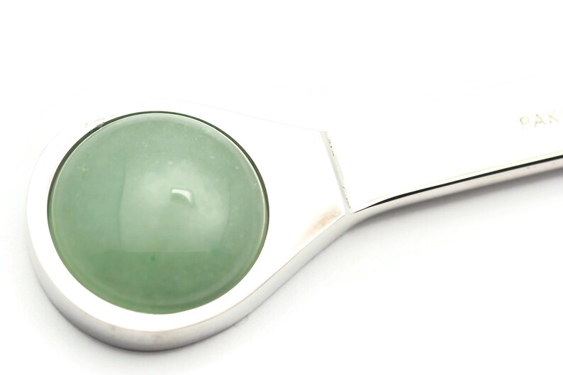 Puede incluir: Un llavero de plata con una piedra de jade redonda verde.