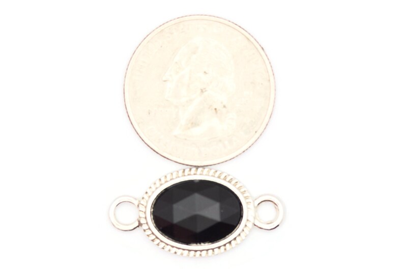 May include: Silver oval connector with a black faceted gemstone. The connector has two loops for attaching jewelry.