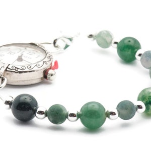 May include: A silver pocket watch with a green agate bead bracelet. The watch face has black Roman numeral hour markers and a silver second hand.