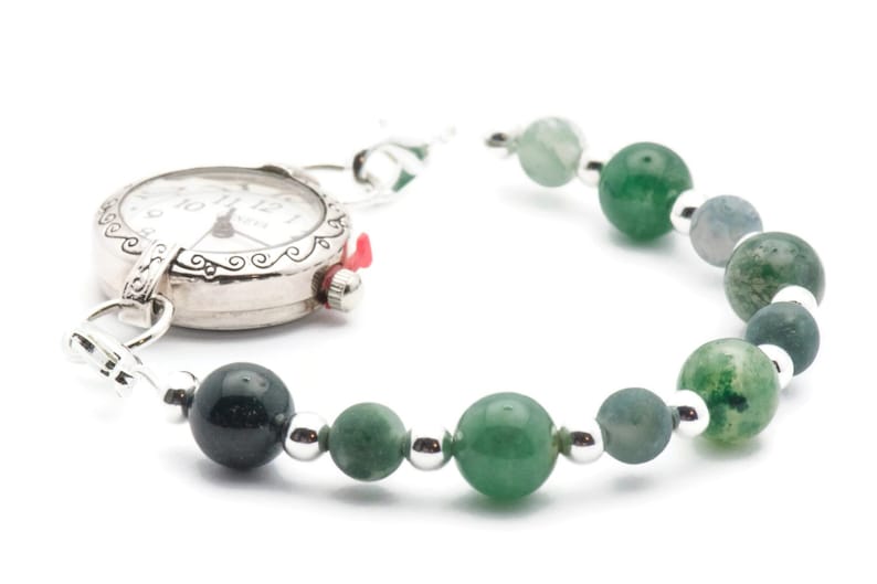 May include: A silver pocket watch with a green agate bead bracelet. The watch face has black Roman numeral hour markers and a silver second hand.