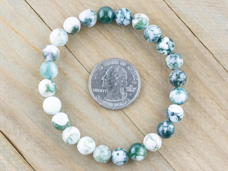 May include: A green and white agate stone beaded bracelet. The bracelet is made of round beads and is approximately the size of a US quarter.