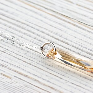 May include: A silver chain necklace with a light brown crystal pendant. The pendant is a long, rectangular shape with a faceted design.