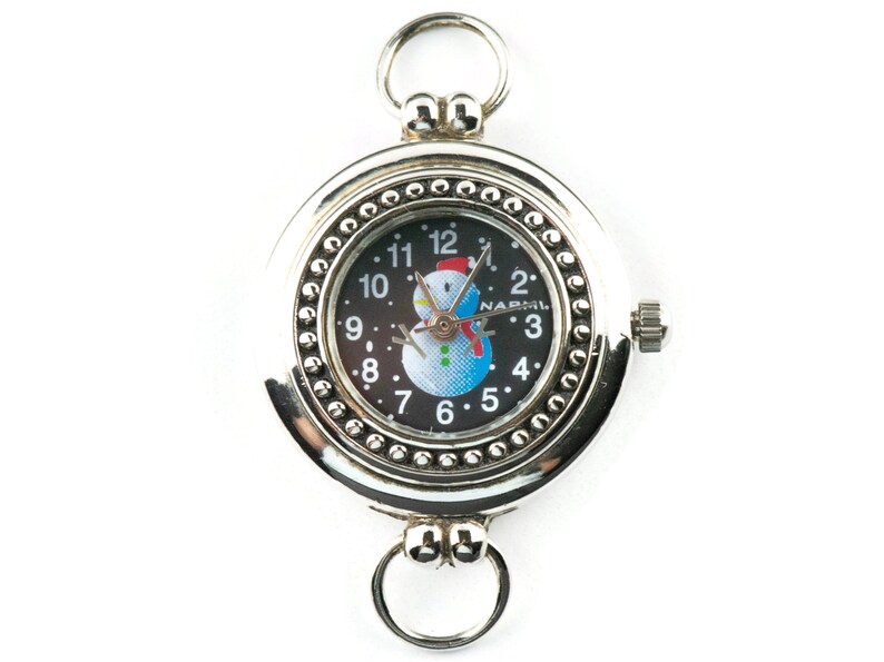May include: Silver pocket watch with a black face and a snowman design. The watch face has black Roman numeral hour markers and a white background with a snowman in the center. The watch has a silver chain attached to the top.