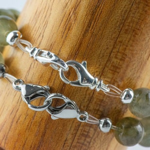 Pode incluir: Dois fechos de prata em um bracelete de contas de pedras preciosas verdes.