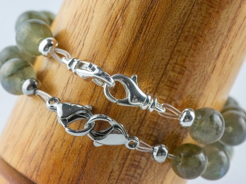 Pode incluir: Dois fechos de prata em um bracelete de contas de pedras preciosas verdes.