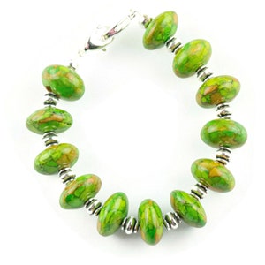 Pode incluir: Um bracelete de pedra com padr&atilde;o verde e marrom com contas prateadas e um fecho prateado.