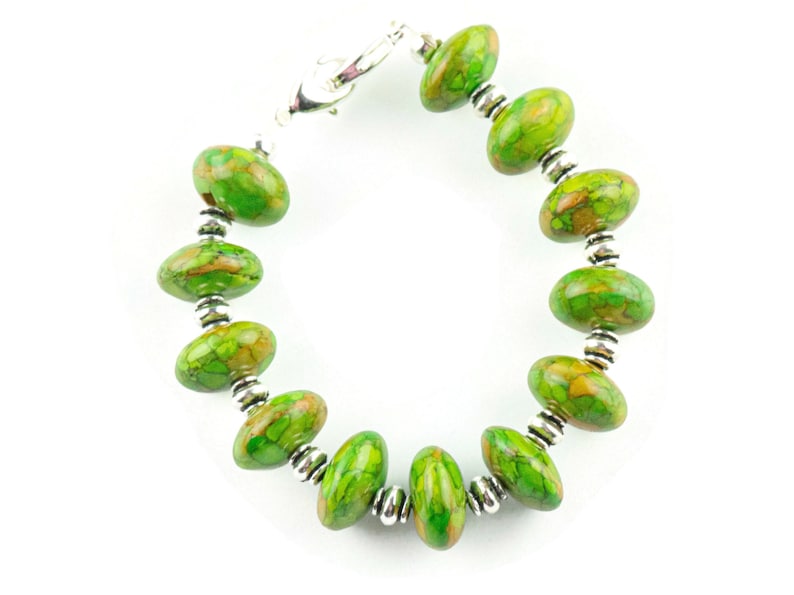 Pode incluir: Um bracelete de pedra com padr&atilde;o verde e marrom com contas prateadas e um fecho prateado.