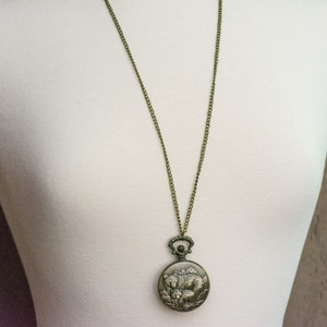 May include: A bronze chain necklace with a round pendant featuring an engraved image of two bears. The pendant is attached to the chain with a small loop.