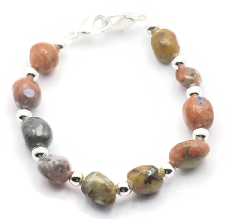 May include: A bracelet made with brown, gray, and orange stones with silver beads and a silver clasp.