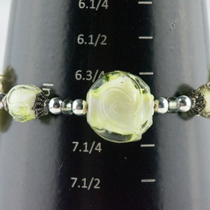 Peut inclure: Un bracelet en verre vert et blanc avec des perles argent&eacute;es. Le bracelet a une circonf&eacute;rence de 7 1/4 pouces.