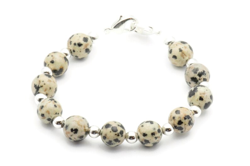 May include: A bracelet made with dalmatian jasper beads and silver spacers. The bracelet has a silver clasp.