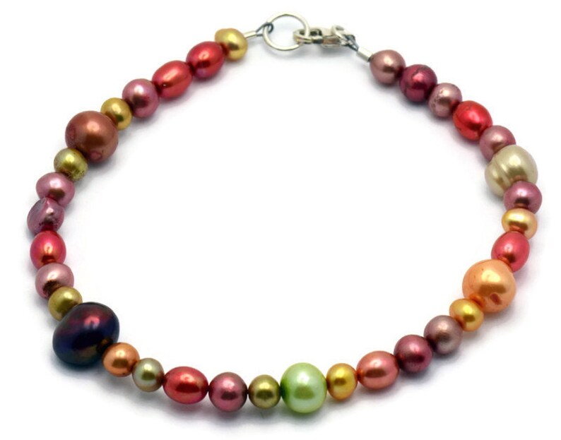 Pu&ograve; includere: Un braccialetto di perle multicolori con una chiusura argentata. Le perle sono in tonalit&agrave; di rosa, rosso, arancio, giallo e verde.