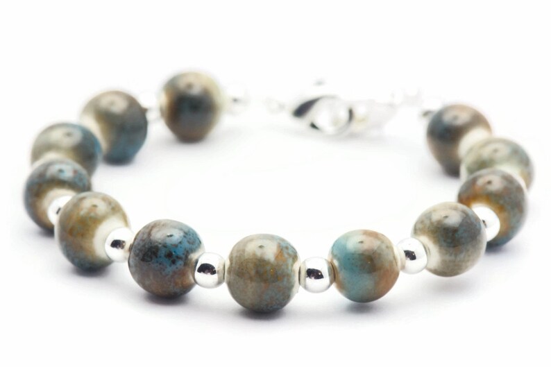 Pode incluir: Um bracelete feito de contas de cer&acirc;mica azul e marrom com espa&ccedil;adores prateados.