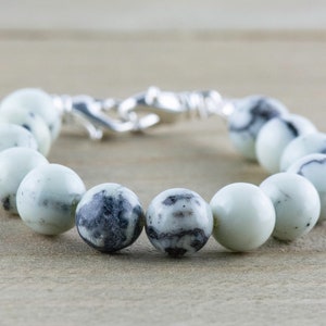 Peut inclure: Un bracelet en perles de pierre tachet&eacute;es de blanc et de noir avec un fermoir argent&eacute;.