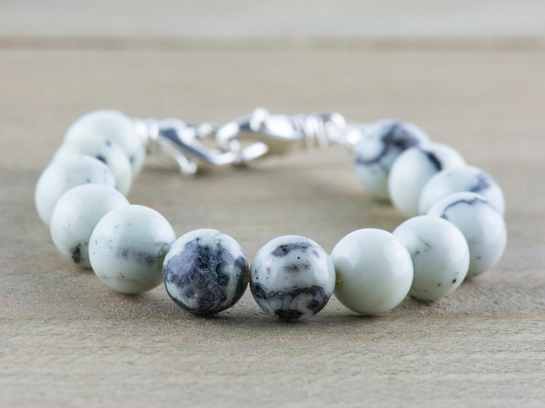 Peut inclure: Un bracelet en perles de pierre tachet&eacute;es de blanc et de noir avec un fermoir argent&eacute;.