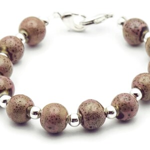 May include: A bracelet made of brown and pink speckled beads with silver accents.