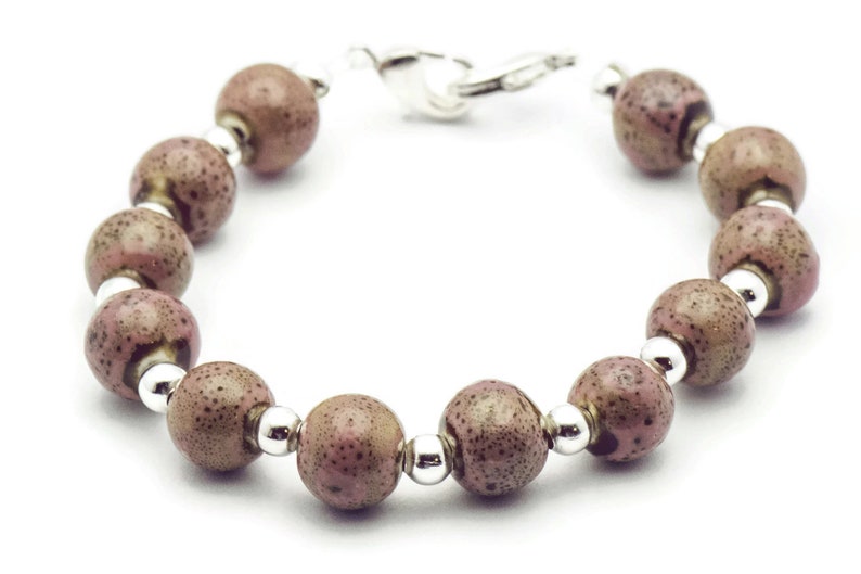 May include: A bracelet made of brown and pink speckled beads with silver accents.