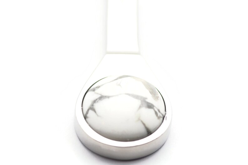 May include: A silver pendant featuring a white and grey marbled stone inlay.