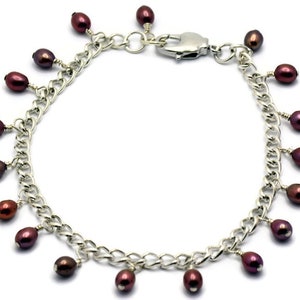 May include: A silver chain bracelet with a lobster clasp and multiple dangling maroon pearls.