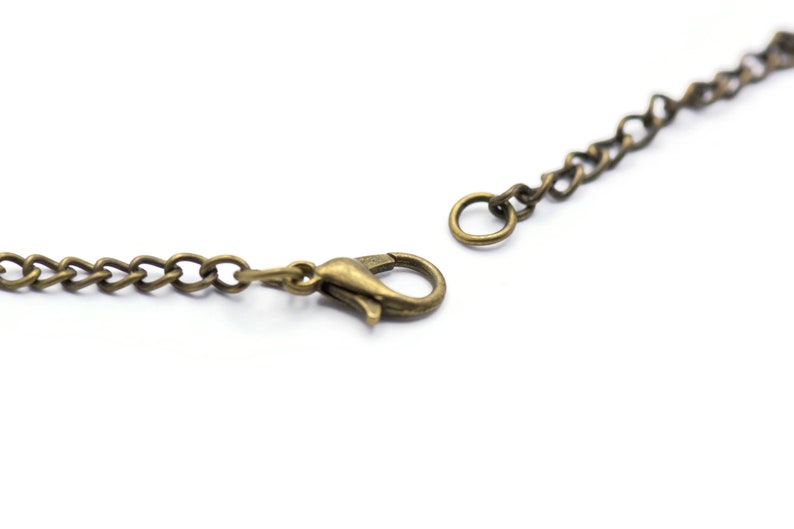 Może przedstawiać: Zbliżenie na złoty łańcuszek z zapięciem na karabińczyk.