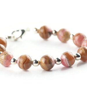 May include: A pink and brown gemstone bracelet with silver beads and a clasp.