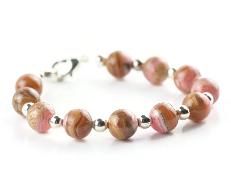 May include: A pink and brown gemstone bracelet with silver beads and a clasp.
