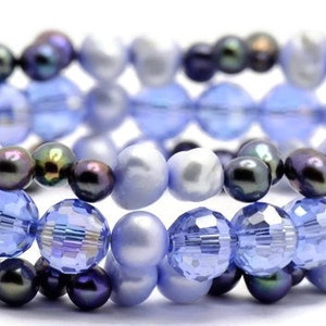 May include: A multi-strand bracelet featuring a combination of light blue and dark blue glass beads and iridescent white pearls.