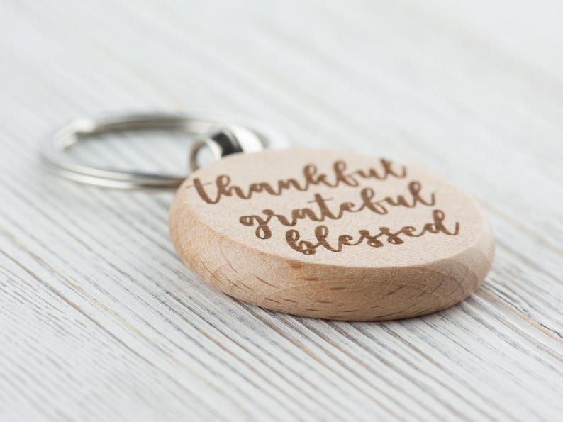May include: A wooden keychain with a round charm that says "thankful grateful blessed" in a cursive font.