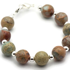 May include: A bracelet made with brown, green, and white jasper beads and silver spacers.
