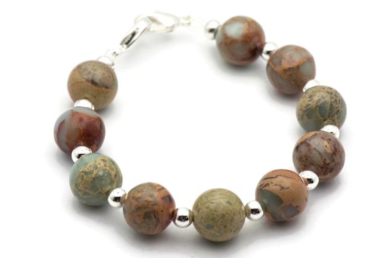 May include: A bracelet made with brown, green, and white jasper beads and silver spacers.