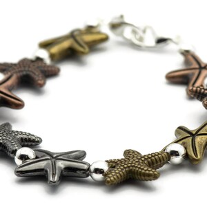 May include: A silver chain bracelet with multiple starfish charms in different colors, including copper, gold, and black.