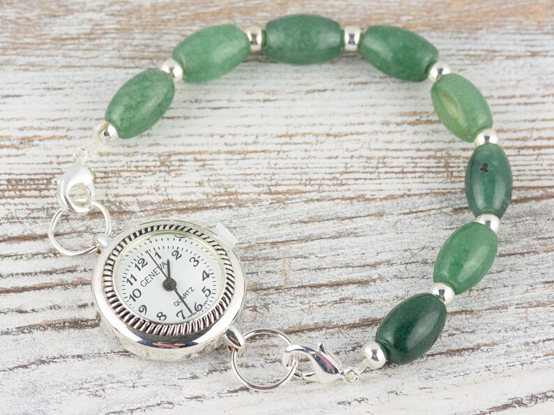 May include: A silver pocket watch with a white face and black hands. The watch is attached to a green jade bead bracelet with silver spacers.