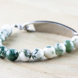 May include: A green and white agate beaded bracelet with a silver clasp and a silver bar charm.