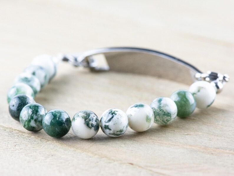 May include: A green and white agate beaded bracelet with a silver clasp and a silver bar charm.