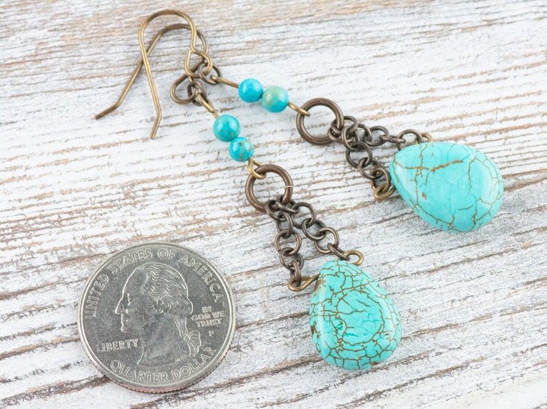 May include: Turquoise and bronze dangle earrings with a teardrop shaped turquoise stone and a chain of bronze beads. The earrings are about the size of a US quarter.