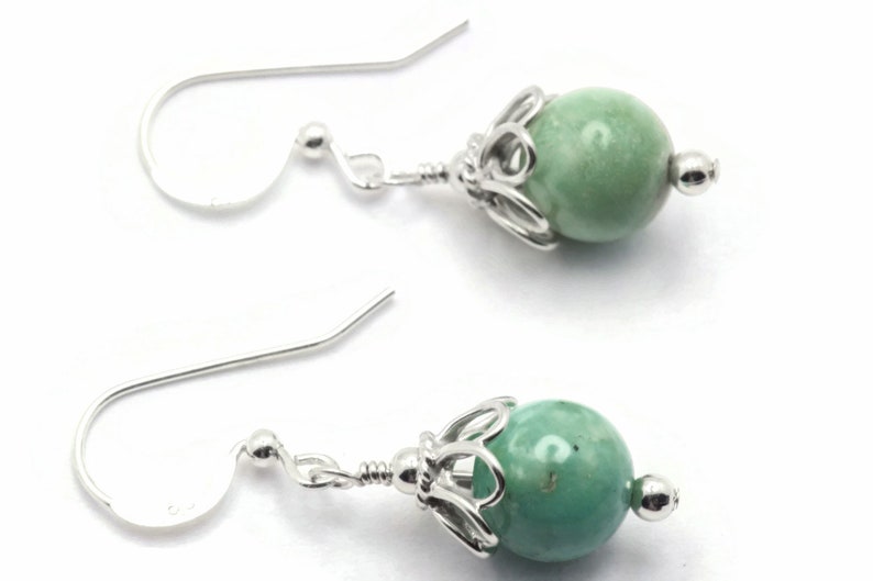Puede incluir: Un par de pendientes de plata con cuentas de piedras preciosas verdes. Las cuentas est&aacute;n engastadas en un dise&ntilde;o de filigrana de plata.