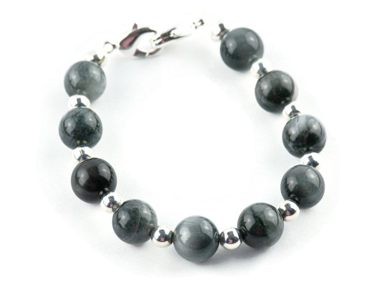 May include: A bracelet made of dark gray gemstone beads with silver spacers. The bracelet has a silver clasp.