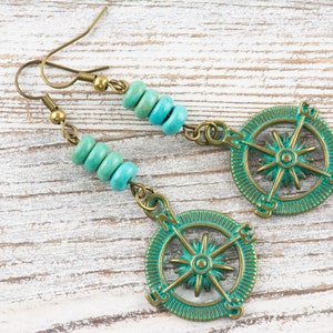 May include: Teal and gold compass earrings with turquoise beads. The compass features a star in the centre and the directions north, south, east, and west.
