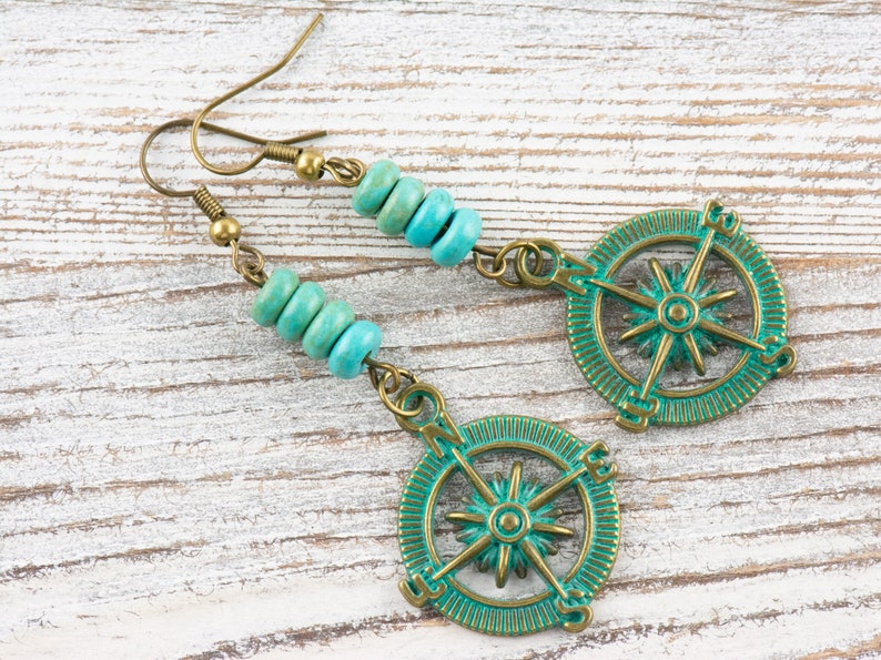 May include: Teal and gold compass earrings with turquoise beads. The compass features a star in the centre and the directions north, south, east, and west.