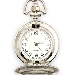 Op de afbeelding: Een zilveren zakhorloge met een witte wijzerplaat en zwarte cijfers. Het horloge is open en de wijzers staan op 10:10. Het horloge heeft een quartz uurwerk.